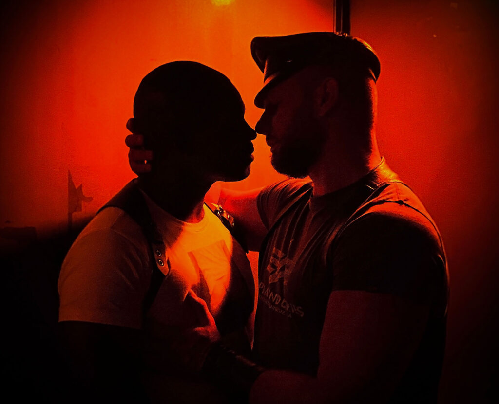 Two sexy men embrace in a darkroom